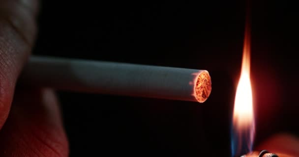 Hombre fumando un cigarrillo contra fondo negro, en tiempo real 4K — Vídeo de stock