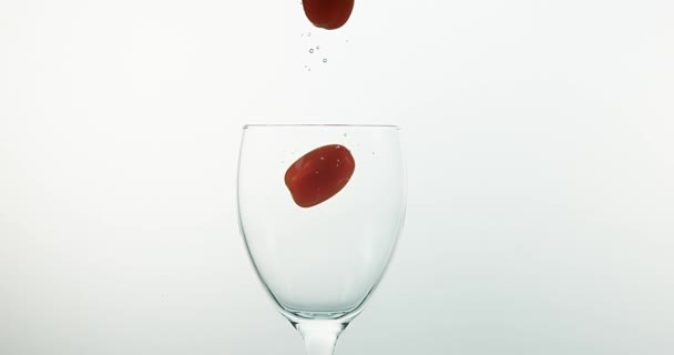 Körsbärstomater, Solanumlycopersicum, frukt som faller i vattnet mot vit bakgrund, Slow Motion 4k — Stockvideo