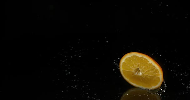Naranja, cítricos sinensis, Fruta que enciende el agua contra el fondo negro, cámara lenta 4K — Vídeo de stock