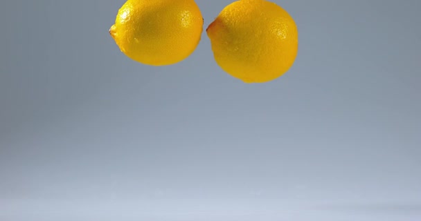 Желтые лимоны падают на воду — стоковое видео