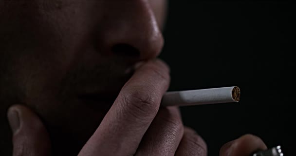 Hombre fumando un cigarrillo contra fondo negro, cámara lenta 4K — Vídeo de stock