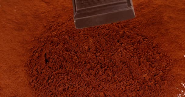 Tableta de chocolate cayendo en polvo de chocolate — Vídeos de Stock