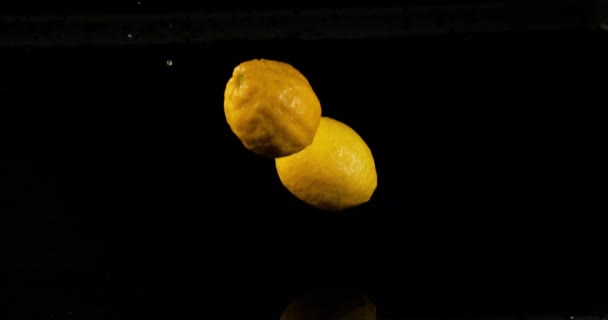 レモンイエロー シトラスライム 黒の背景に水に落ちる果物 スローモーション4K — ストック動画