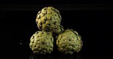 Enginar, Cynara scolymus, Sebzeler Kara Arkaplanda Suya Düşüyor, Ağır çekim 4k