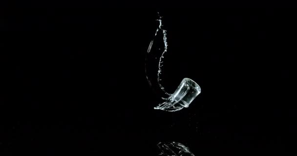 黒の背景に水のバウンスとスプラッシングのガラス スローモーション4K — ストック動画