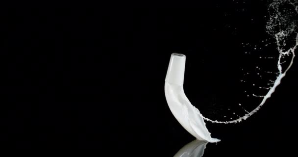 Verre de lait rebondissant et éclaboussant sur fond noir, mouvement lent 4K 