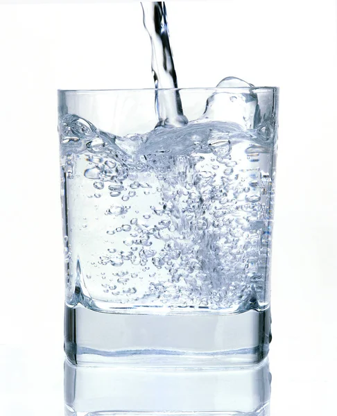 Νερό Που Χύνεται Ένα Ποτήρι Ενάντια Στο Λευκό Φόντο — Φωτογραφία Αρχείου