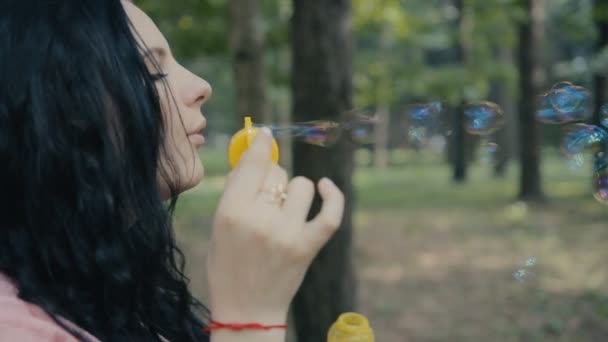 Девушка надувает пузыри на открытом воздухе крупным планом — стоковое видео