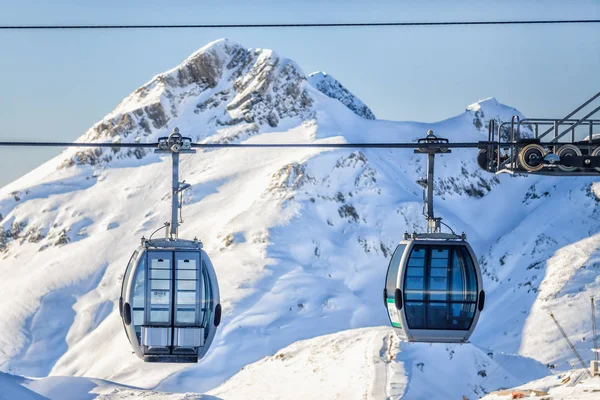 Two cableway ski lift cabins on snowy mountain background