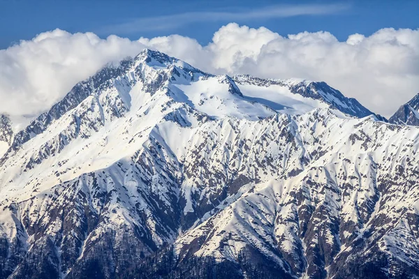Bela paisagem montanhosa do cume caucasiano principal com pico nevado no fundo azul do céu nublado — Fotografia de Stock