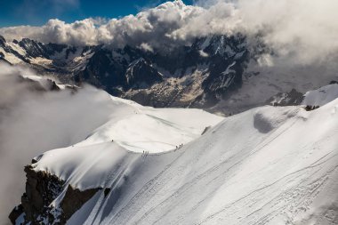 bir grup dağcı uçurumun üzerinde bir dağ sırtı üzerinde yürüyen