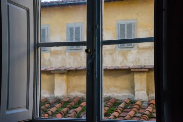 Kiremitli çatıda ahşap panjurlar ve pencereleri olan bir duvara sahip eski bir İtalyan penceresinden manzara