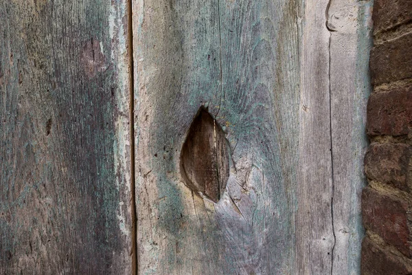Arka plan: delik li iki eski dikey tahtalar ve tuğla duvar küçük bir parçası