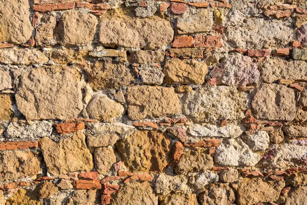 Arka plan: kapsayıcı tuğla ve taşlarla kumtaşı bir duvar