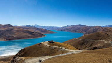 Yüksek irtifa lake parlak mavi, bir yol, bir küçük köşk ve bir dağ mesafe için bir dağ geçidi görüntüleyin.