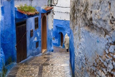 Adam mavi şehir yağmurda sokakta yürürken