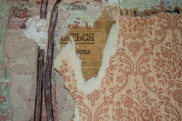 Eski gazete bir parça ile alçı ve sağlam duvar kağıdı dışarı yapışan iki eski teller