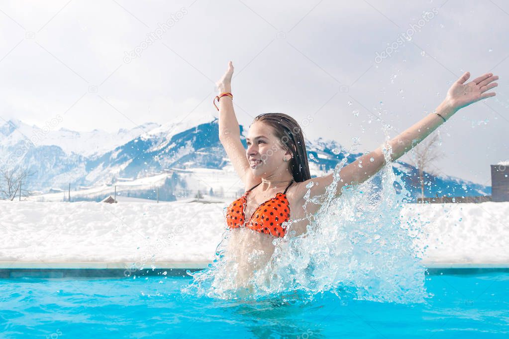Geothermal Spa. The girl enjoys swimming in blue water on the background of snowy mountains.