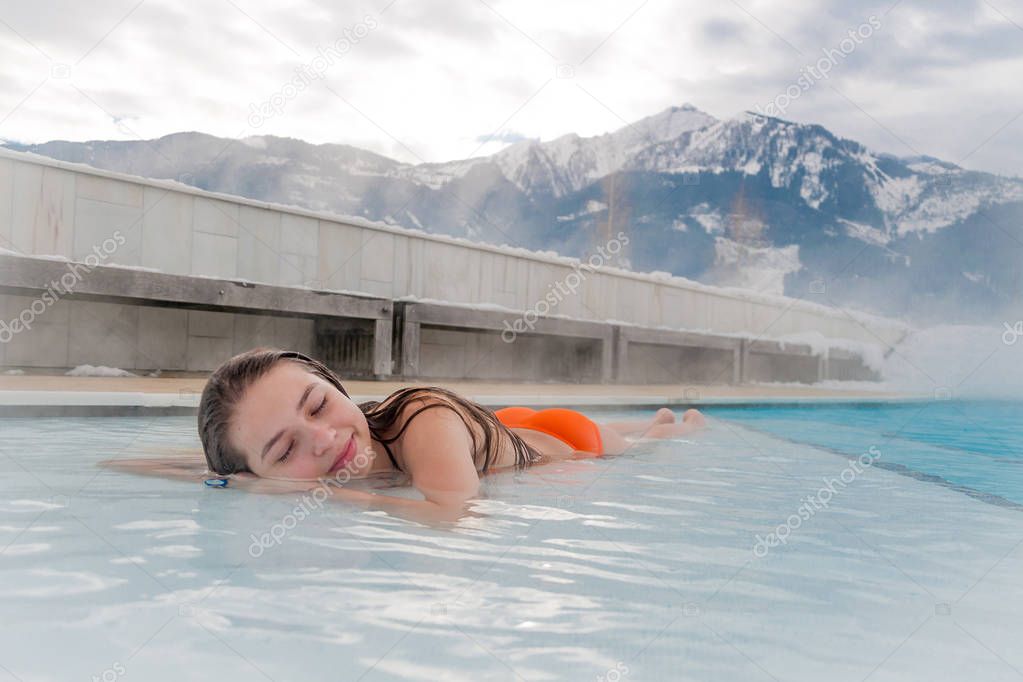 young woman relaxing in hot springs in winter