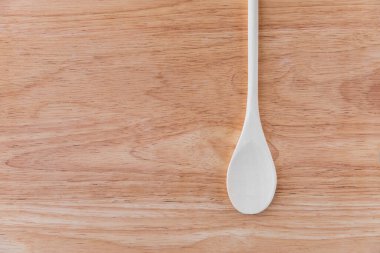 Boş beyaz ahşap kaşık açık kahverengi tahta bir tahtanın üzerinde leke ile yatar. Bir kafe ya da restoran menüsü için şaşırtıcı bir geçmiş, tabela