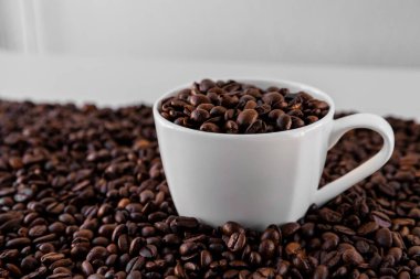 Beyaz kupa, her yerde kavrulmuş kahve çekirdekleri, kupanın içinde ve etrafında beyaz arka planda bir sürü şey var. Kafeye, restorana, kafeterya menüsüne ya da Sig olarak gitmek için harika.