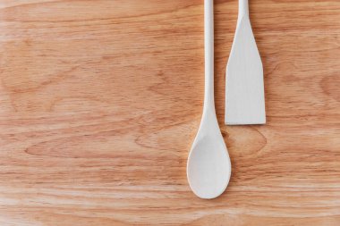 Beyaz ahşap kaşık ve spatula açık kahverengi tahta bir tahtanın üzerinde leke ile yan yana yatıyorlar. Bir kafe veya restoran menüsü için şaşırtıcı bir geçmiş, işaret yaban domuzu
