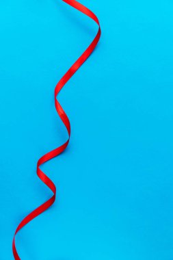 Mavi arka plan dikey dalgalı kırmızı kurdele. Kopyalama. Uzayı kopyala Kartpostal Metin için arka plan. Bir bilgisayar için duvar kağıdı.
