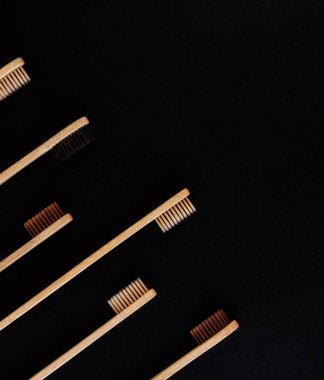 Siyah arka planda bir grup eko bambu diş fırçası. Farklı renkte. Üst görünüm, boşluğu kopyala. Ağız temizliği için doğal organik ürün. Dişçi sıfır atık ve plastik konsept yok. Dünya için güvenli.. 