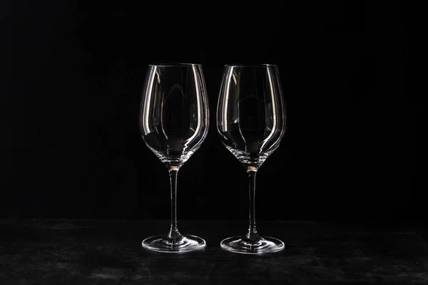 暗いテーブルの上の黒い背景に隔離されたワインの2つのガラス 内部に興味深い反射で透明なガラスを空にします コピースペース 新しいビューの上 — ストック写真