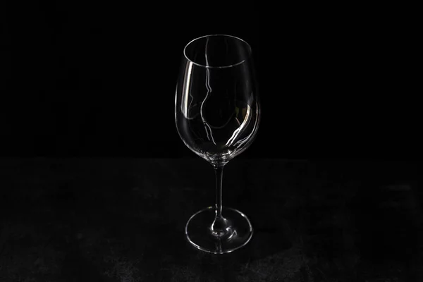 黒の背景に隔離されたワインのガラス 女性の体の屈曲に似た 内部に興味深い反射を持つ空の透明なガラスのシルエット コピースペース 新しいビューの上 — ストック写真