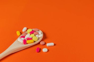 Karışık ilaç hapları, tahta kaşıkta haplar turuncu arka planda. Bir sürü farklı hap ve tablet. Sağlık hizmetleri. Üst Manzara. Mesaj için yer var. Uzayı kopyala Yeni imaj. Eczacılık hapları. Yakın çekim..