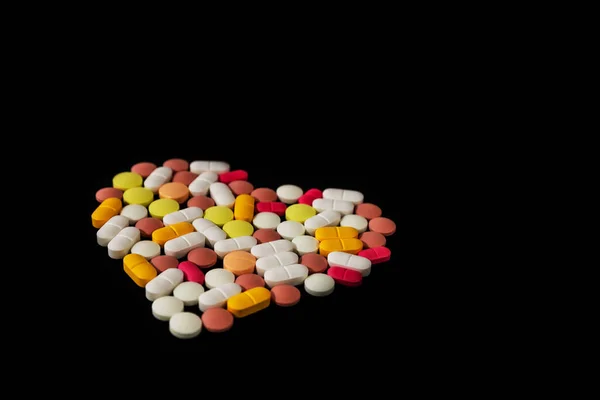 黒の背景に心の形で折り畳まれた多くの異なる薬や錠剤 テキストのためのスペースを持つ多くの薬や錠剤 健康管理 最上階だ コピースペース 新しいイメージ 閉鎖だ 接近中だ ソフトフォーカス — ストック写真