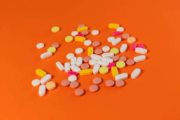 Different medicine pills, tablets on orange background. Many medicine pills and tablets with place for text. Health care. Top view. Copy space. New image. Pharmaceutical pills. Closeup. Soft focus