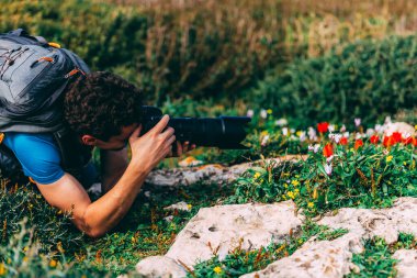 Kıvırcık saçlı yakışıklı genç bir adam ilk laleleri fotoğraflıyor. Mavi tişörtlü ve gri sırt çantalı, telefoto lensli bir adam çiçeklerin fotoğraflarını çekiyor. İsrail 'de yürüyüş