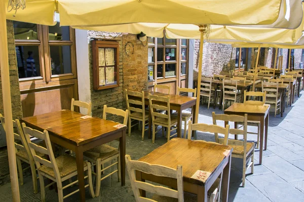 Mesas y sillas de café fuera de un pintoresco edificio de ladrillo en Toscana, Italia — Foto de Stock