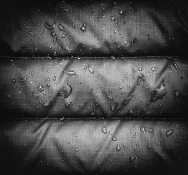 Z bliska niebieski deszcz wodoodporna kurtka tkaniny z kropelek wody, efekt winiety. — Zdjęcie stockowe