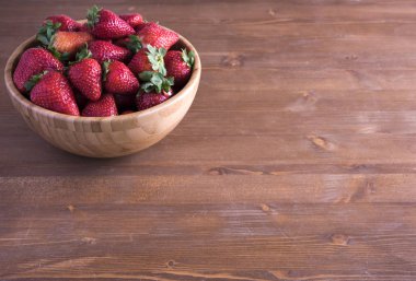 Rustik ahşap masa üzerinde kase taze olgun kırmızı çilek. 