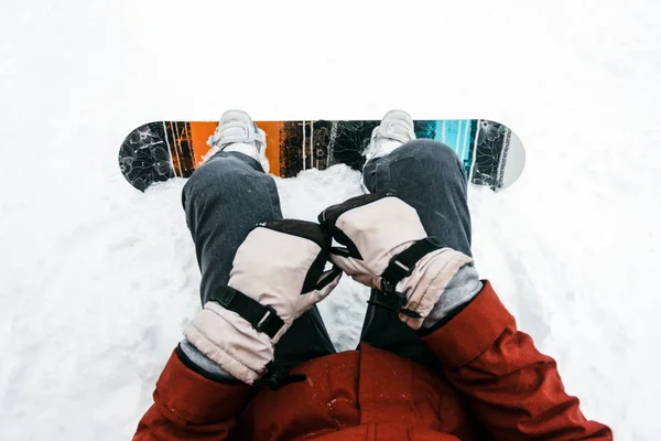 Αγνώριστος ο άνθρωπος βάζοντας στο snowboard του και σφίγγοντας τα λουριά σε φόντο του χιονιού το χειμώνα, άποψη — Φωτογραφία Αρχείου