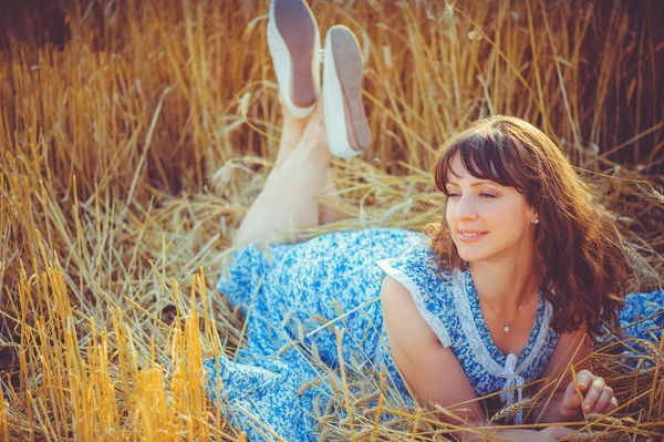 Девушка лежит на пшеничном поле во время — стоковое фото