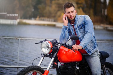 trendy adam telefonda konuşurken bir motosiklet üzerinde