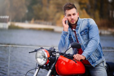 trendy adam telefonda konuşurken bir motosiklet üzerinde