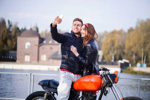 Парень на мотоцикле с девушкой, делающей селфи — стоковое фото