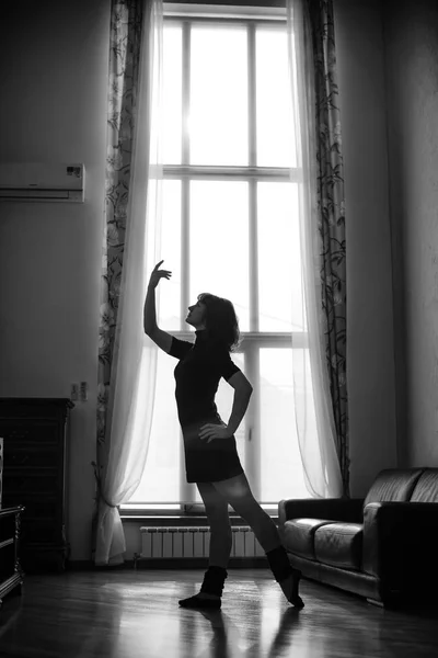 young woman dancing at home by the window