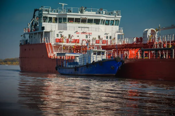 Blauer Schlepper hilft einem großen Öltanker. — Stockfoto