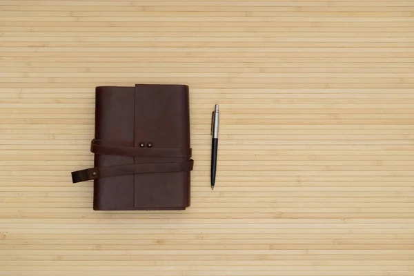 Escritório com um velho caderno de couro e caneta — Fotografia de Stock