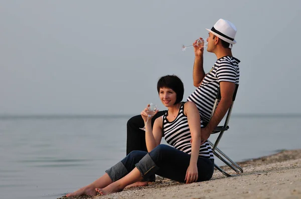 Casal sentado na praia com vinho — Fotografia de Stock