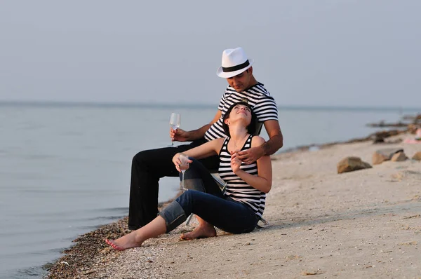 Pareja sentada en la playa con vino — Foto de Stock