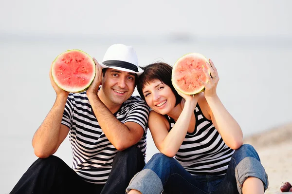 Casal sentado na praia com melancia — Fotografia de Stock