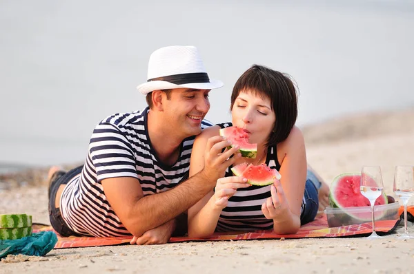 Casal sentado na praia com melancia — Fotografia de Stock