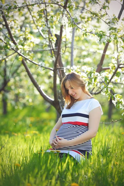 Беременная молодая женщина в цветущем саду весной — стоковое фото